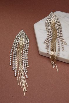 Rock a slithery sleek statement look wearing this pair of earrings! The gold-tone multi snake chain with multi rhinestone drop earrings. DIMENSION length: 4.5" width: 1" earring back: Post metal finish: Gold Plating Gold Long Drop Linear Earrings For Party, Gold Chain Metal Earrings For Party, Gold Rhinestone Fringe Metal Jewelry, Gold Chain Earrings For Parties, Gold Metal Jewelry With Rhinestone Fringe, Party Earrings With Gold Chain Detail, Party Earrings With Gold Chain, Glamorous Gold Plated Crystal Earrings For Party, Glamorous Gold Jewelry With Rhinestone Fringe