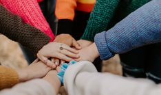 four people holding hands together with their fingers on top of each other's hand