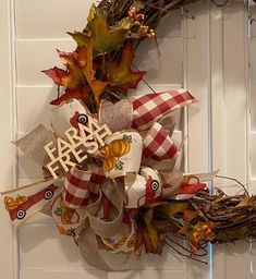 a wreath with the words farm fresh on it hanging on a white door handle and decorated with autumn leaves