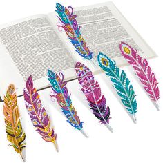 five colorful feathers are on top of an open book