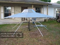 a blue umbrella sitting on top of a metal pole in front of a house next to a car