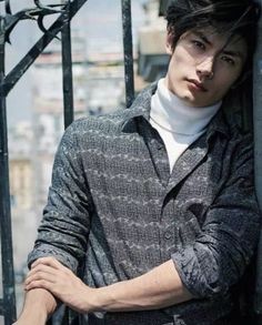 a young man leaning against a metal fence