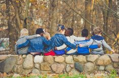 a group of children sitting on top of a stone wall