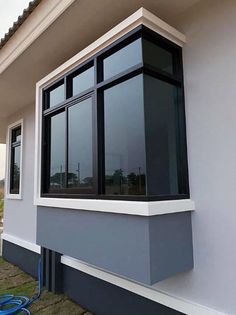 a house with black windows and white trim on the side of it, next to a blue hose