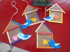 four bird houses made out of popsicle sticks on top of a red table next to a potted plant