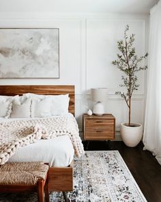 a bedroom with a bed, rug and two nightstands in front of a painting on the wall