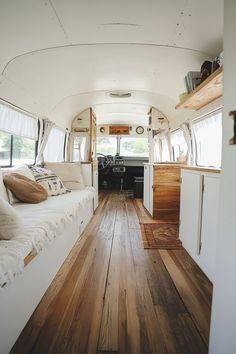 the interior of an rv with wood flooring and white walls, windows, and couches