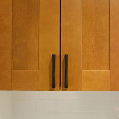 a kitchen with wooden cabinets and white counter tops, black handles on the cabinet doors