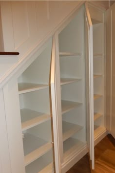 an empty white bookcase in the corner of a room next to a stair case