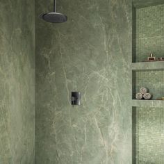 a bathroom with green marble walls and floor tiles on the shower wall, along with shelving