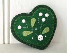 a green heart shaped ornament hanging on a white door with buttons and thread