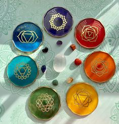 four colorful plates with gold designs on them sitting on top of a table covered in flowers