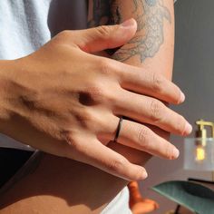 a person wearing a ring on their left hand, with tattoos on her right arm