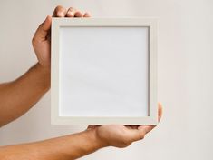 a person holding up a white frame with an empty space in it to display something