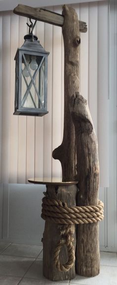 a lantern hanging from the side of a wooden pole next to a tree trunk and rope