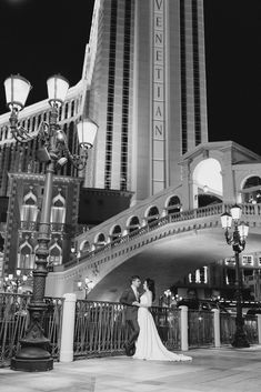 a bride and groom pose in front of the venetian las vegas hotel & casino at night