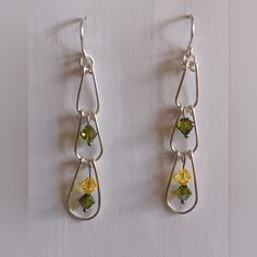 two dangling earrings with yellow flowers and green glass beads on silver earwires against a white background