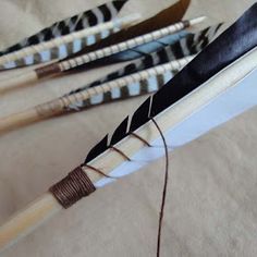 three arrows with black and white feathers on them are tied to a piece of paper