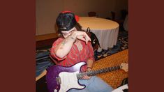 a person sitting on the floor with a guitar in front of them and covering their eyes