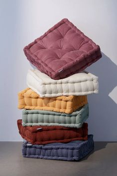 a stack of pillows sitting on top of each other in front of a white wall