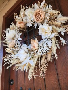 a wreath with flowers and feathers hanging on a door