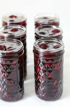 several jars filled with cherries sitting on top of a table