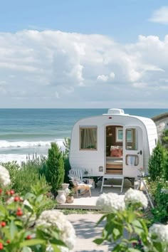 an rv parked on the side of a road next to flowers and trees with water in the background