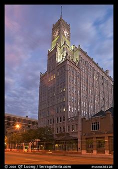 a tall building with a clock on it's side at night time in the city