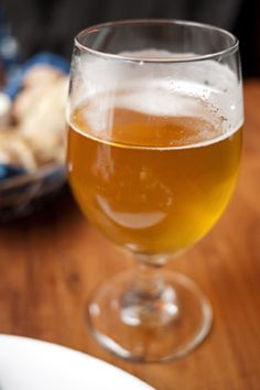 a glass of beer sitting on top of a table next to a plate of food