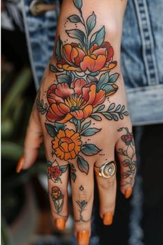 a woman's hand with tattoos and flowers on her left arm, holding onto the wrist