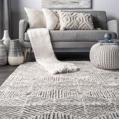 a living room with a gray couch and white rug