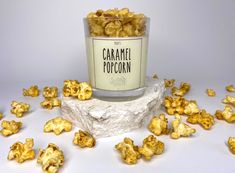 a bucket filled with caramel popcorn sitting on top of a pile of rocks next to it's wrapper