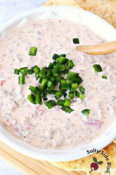 a white bowl filled with dip surrounded by tortilla chips and celery