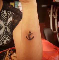 a small anchor tattoo on the left arm and right hand is shown in black ink