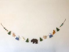 a bear and tree garland hanging on a wall in front of a white painted wall