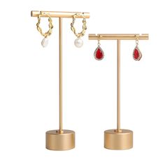 two pairs of earrings with red and white stones on gold stands against a white background