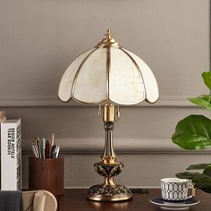 a desk lamp sitting on top of a wooden table next to a cup and saucer