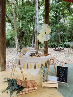 a table with balloons and other items on it in the woods for an outdoor party