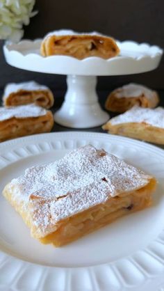 some desserts are sitting on white plates and one is covered in powdered sugar