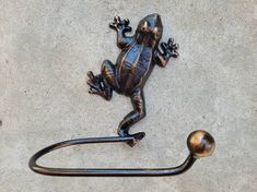 a metal frog sitting on top of a hook