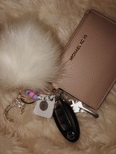 a keychain, wallet and other items are laying on a fur surface