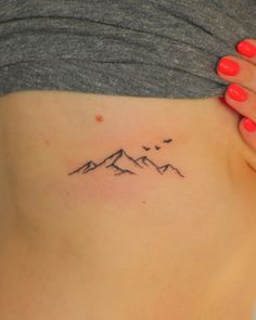 a woman's lower back tattoo with birds flying over the mountains