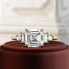 an emerald cut diamond ring with three diamonds on top