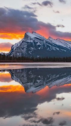 the mountains are reflected in the still water at sunset, with pink and orange clouds