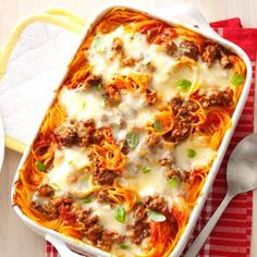 a casserole dish with meat, cheese and sauce in it on a red and white checkered cloth