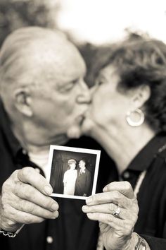 an older couple kissing while holding up a photo