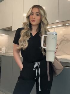 a woman is holding a coffee mug in her hand while standing next to a kitchen counter