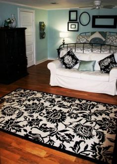 a living room with a white couch and black and white rugs on the floor