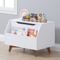 a white toy chest with books and toys in it