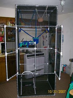 a kitchen area with an oven, refrigerator and wire mesh cage on the wall above it